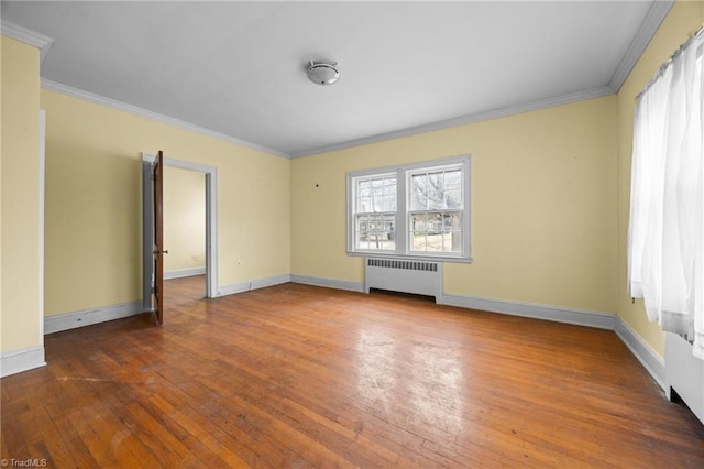 spare room featuring crown molding, radiator heating unit, baseboards, and hardwood / wood-style floors