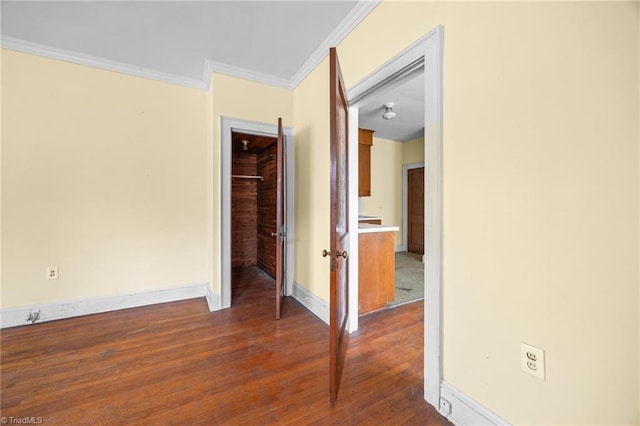 empty room with crown molding, baseboards, and dark wood-style flooring