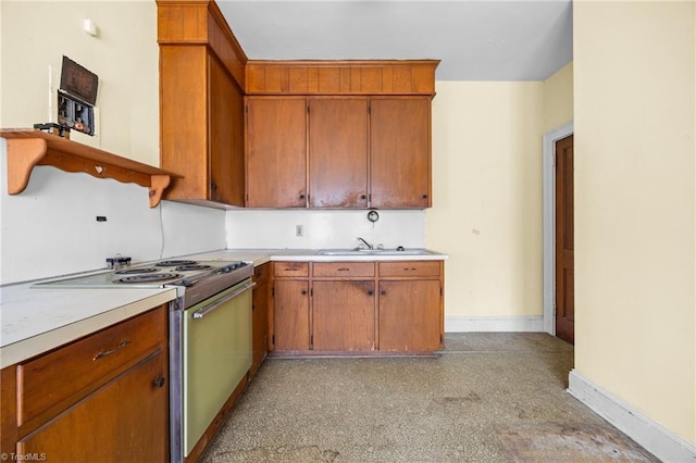 kitchen with baseboards, light countertops, electric range oven, brown cabinetry, and a sink