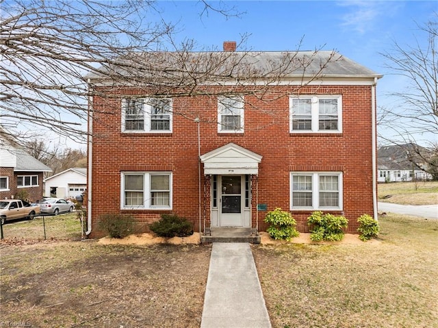 view of front of property with a front yard, brick siding, a chimney, and fence