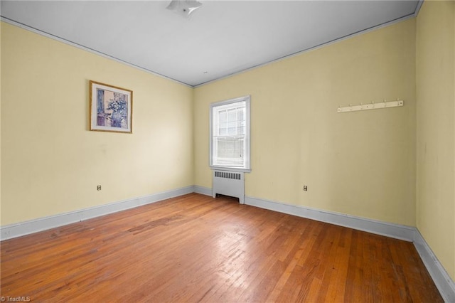 unfurnished room with baseboards, radiator, and hardwood / wood-style floors