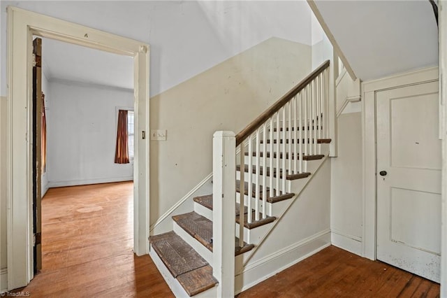 staircase featuring baseboards and wood finished floors