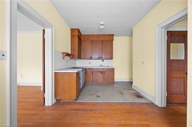 kitchen with light wood-type flooring, brown cabinets, baseboards, and light countertops