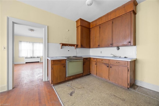 kitchen with brown cabinets, radiator, light countertops, and electric stove