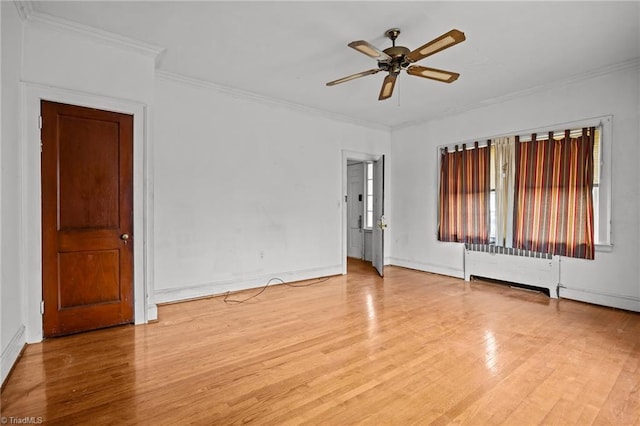 empty room with a ceiling fan, wood finished floors, crown molding, and radiator heating unit