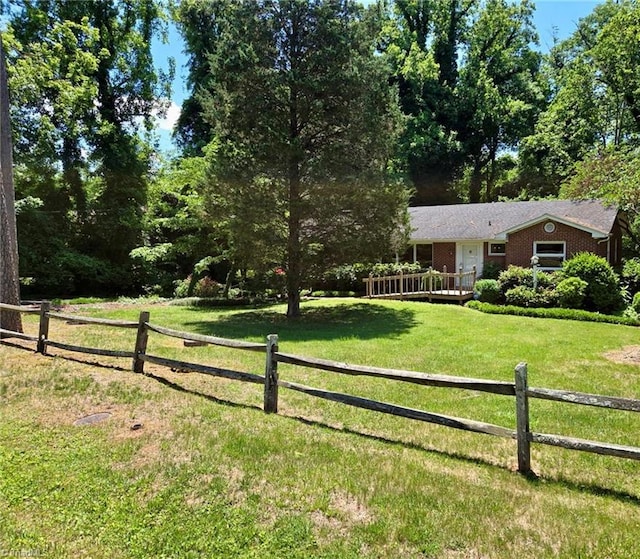 view of front of house with a front lawn, brick siding, fence, and a wooden deck