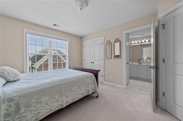 bedroom with ensuite bath, light colored carpet, and a closet