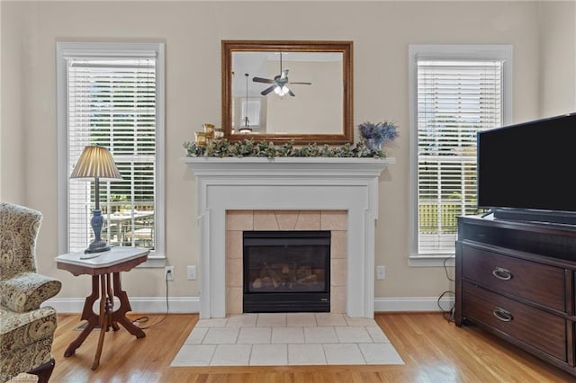 sitting room featuring a tiled fireplace, plenty of natural light, and light wood-type flooring