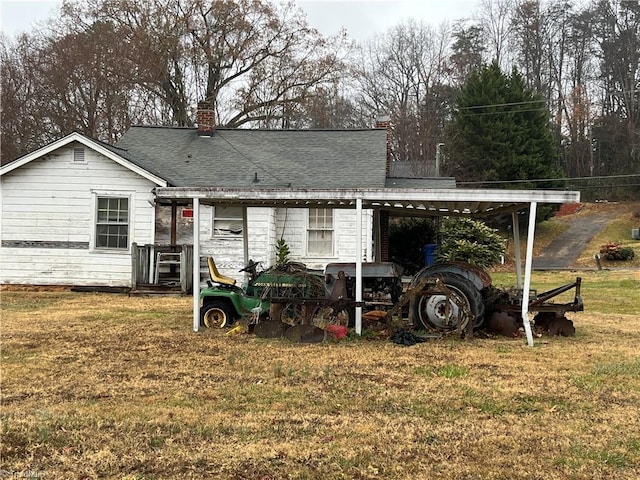 back of property with a carport and a lawn