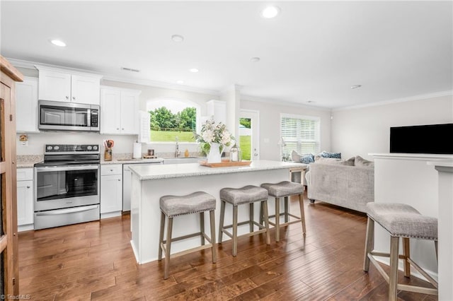 742 Teague Rd, Winston-Salem, NC 27107 - kitchen featuring appliances with stainless steel finishes, ornamental molding, healthy amount of natural light, a kitchen breakfast bar, and white cabinetry