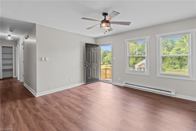 spare room featuring baseboard heating, a ceiling fan, wood finished floors, and baseboards
