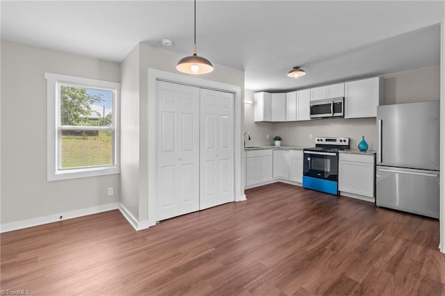 kitchen with appliances with stainless steel finishes, white cabinetry, dark wood-style flooring, and hanging light fixtures