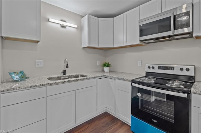 kitchen with stainless steel microwave, electric range, a sink, and white cabinetry