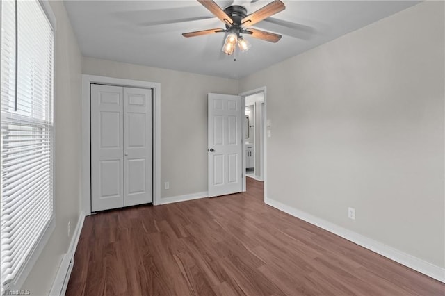 unfurnished bedroom with wood finished floors, baseboards, a closet, and a ceiling fan