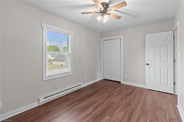 unfurnished bedroom featuring a baseboard radiator, wood finished floors, baseboards, and a closet