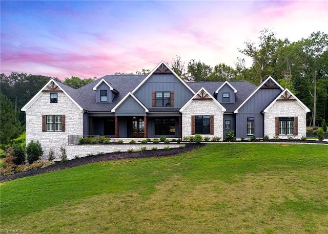 view of front facade featuring stone siding, board and batten siding, and a front yard