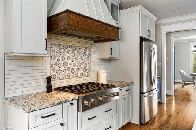 kitchen featuring appliances with stainless steel finishes, tasteful backsplash, white cabinetry, and custom range hood