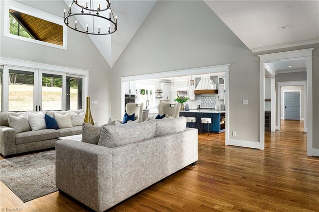 living room with plenty of natural light, dark wood-type flooring, an inviting chandelier, and high vaulted ceiling