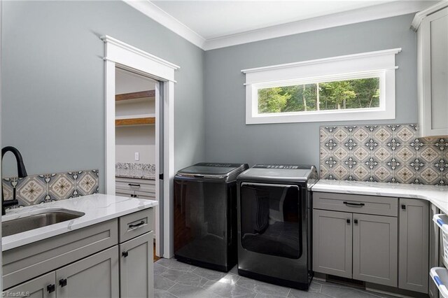 laundry area featuring washer and clothes dryer, ornamental molding, cabinets, and sink