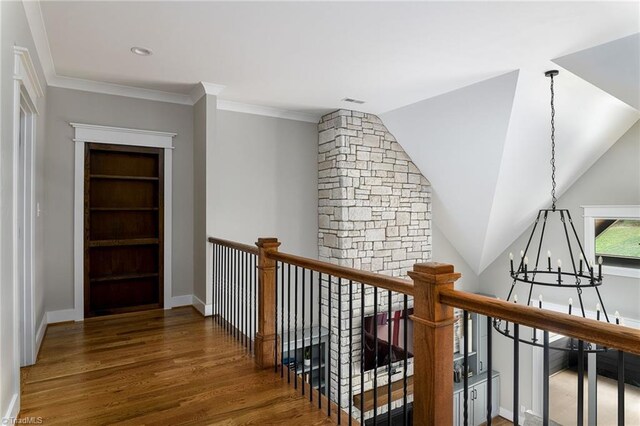 hall featuring dark hardwood / wood-style flooring, built in shelves, crown molding, a chandelier, and lofted ceiling