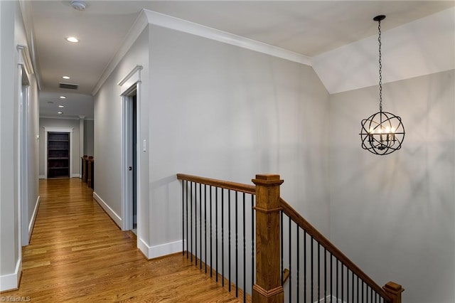 hallway featuring ornamental molding, light wood-type flooring, and a notable chandelier