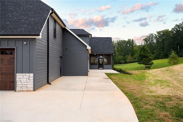 property exterior at dusk with a yard and a garage