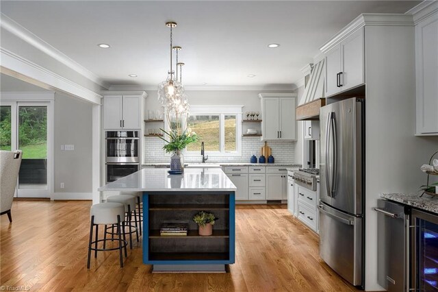 kitchen featuring a kitchen island, light hardwood / wood-style flooring, stainless steel appliances, decorative backsplash, and white cabinets