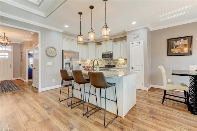 kitchen featuring white cabinets, appliances with stainless steel finishes, light hardwood / wood-style floors, and ornamental molding