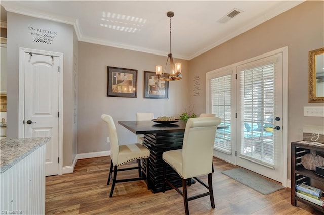 dining room featuring wood-type flooring, a notable chandelier, and ornamental molding