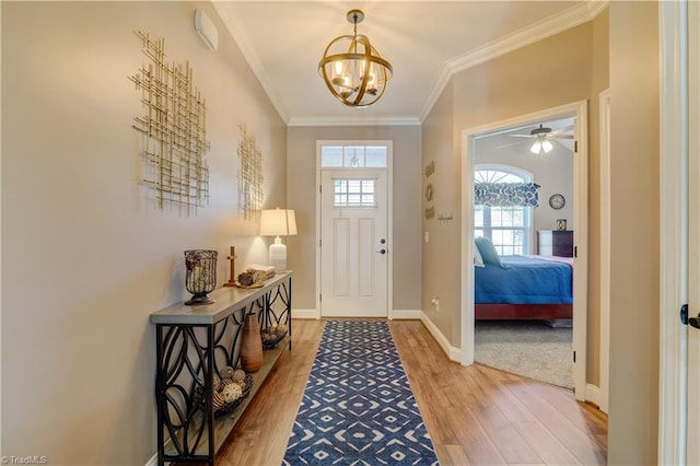 entryway with hardwood / wood-style flooring, ceiling fan with notable chandelier, and crown molding