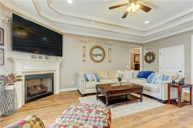 living room with wood-type flooring, a tray ceiling, ceiling fan, and crown molding