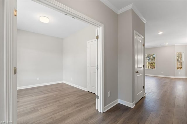 corridor with wood-type flooring and crown molding