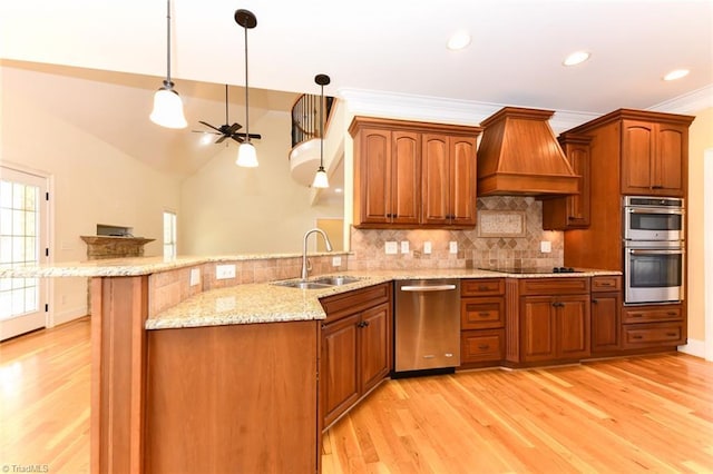 kitchen with sink, decorative light fixtures, custom range hood, and appliances with stainless steel finishes