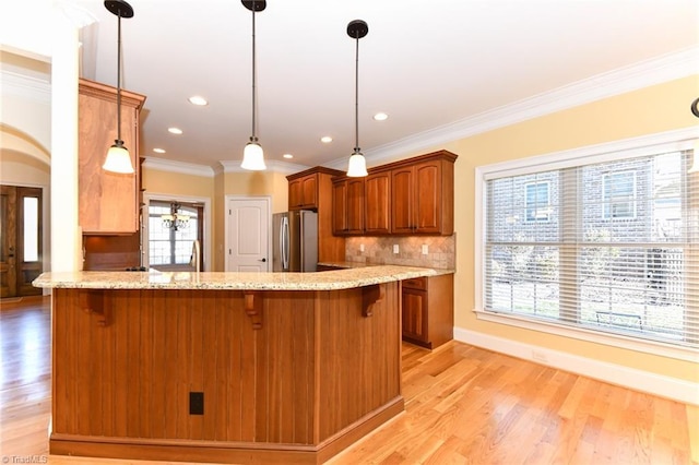 kitchen featuring light stone counters, backsplash, stainless steel fridge, and crown molding