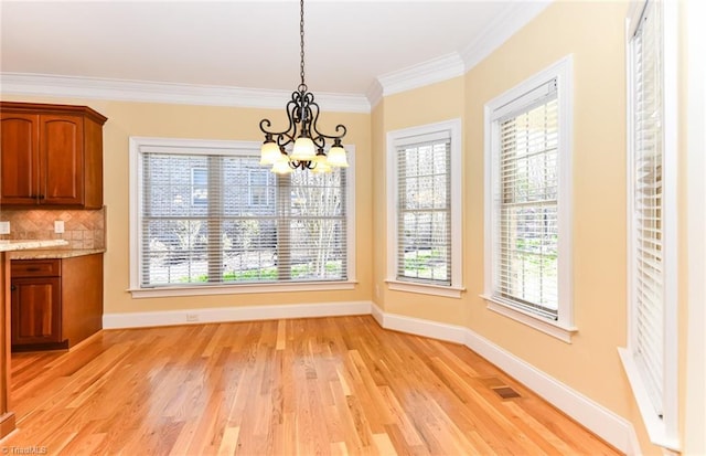 unfurnished dining area with light hardwood / wood-style flooring, ornamental molding, a chandelier, and a healthy amount of sunlight