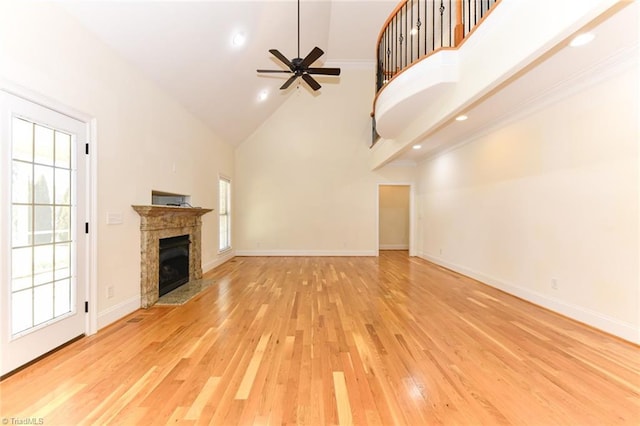 unfurnished living room featuring light hardwood / wood-style flooring, ceiling fan, high vaulted ceiling, and a wealth of natural light