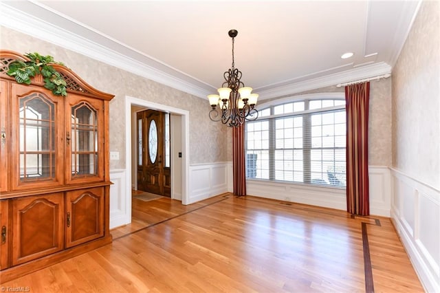 unfurnished dining area with light hardwood / wood-style floors, ornamental molding, and an inviting chandelier