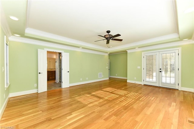 empty room with wood-type flooring, french doors, ornamental molding, ceiling fan, and a tray ceiling