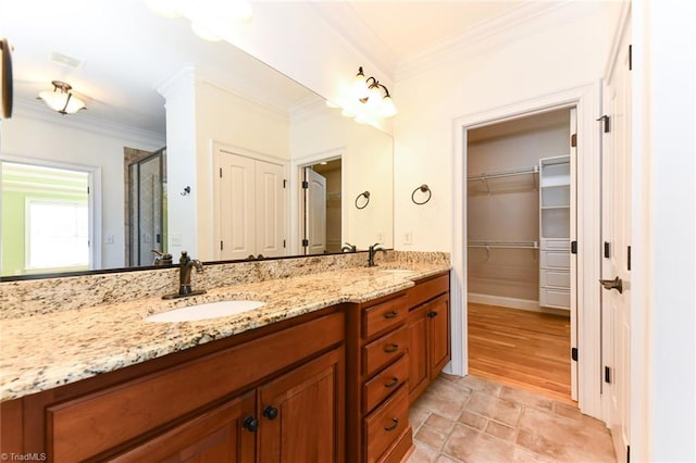 bathroom with a shower with shower door, vanity, and crown molding