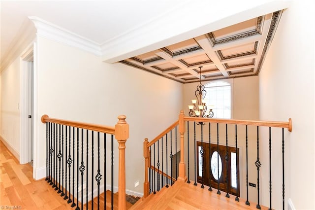 staircase with hardwood / wood-style floors, ornamental molding, coffered ceiling, an inviting chandelier, and beamed ceiling