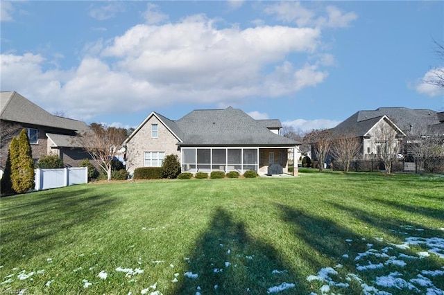 rear view of house featuring a sunroom and a lawn