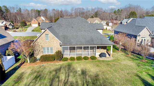 rear view of house featuring a sunroom and a lawn