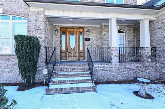 snow covered property entrance featuring a porch