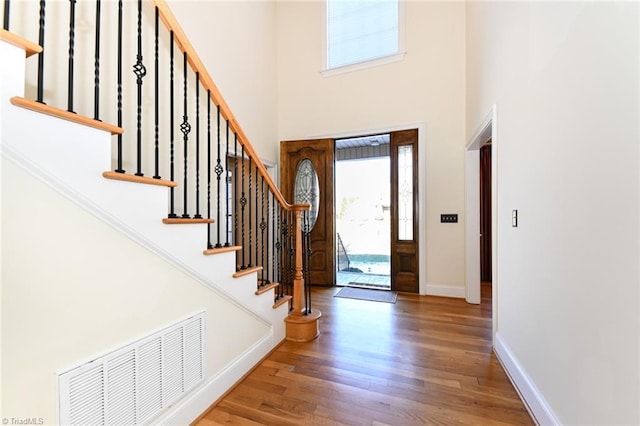 foyer entrance with hardwood / wood-style flooring and a towering ceiling