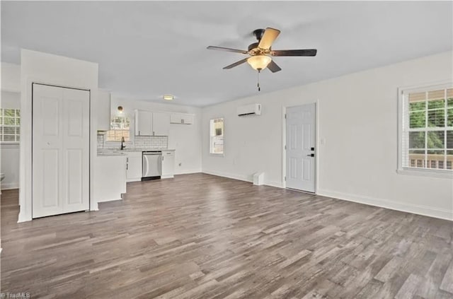 unfurnished living room featuring a ceiling fan, a healthy amount of sunlight, and dark wood-style floors