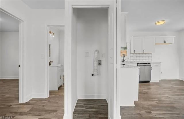 corridor with dark wood-type flooring, baseboards, and a sink