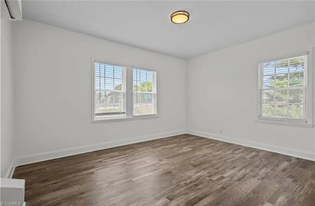 empty room with baseboards and dark wood finished floors
