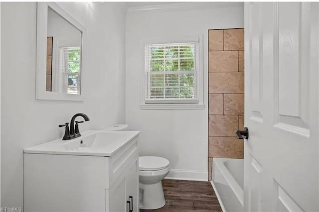 full bathroom featuring a tub, vanity, ornamental molding, toilet, and wood finished floors