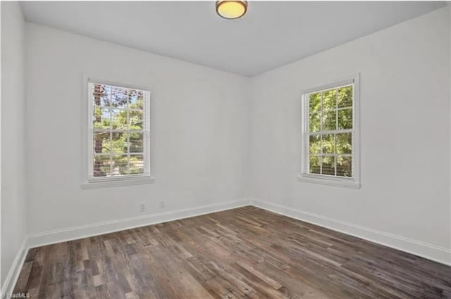 empty room with baseboards and dark wood finished floors