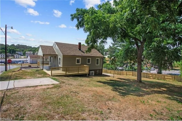 rear view of property with a wooden deck, fence, and a lawn